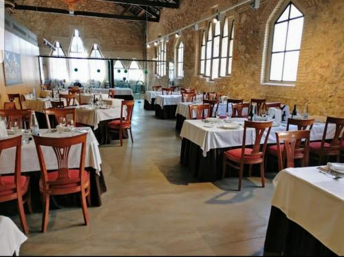 un restaurante con mesas y sillas con manteles blancos en Casa de Danann, en Rasquera