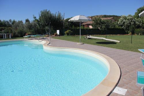 uma grande piscina com um guarda-sol num quintal em Agriturismo Agrifoglio em Capalbio