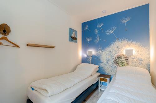 two beds in a room with a blue wall at Anna 224 in De Koog