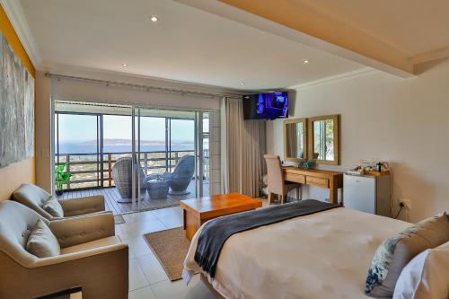 ein Hotelzimmer mit einem Bett, einem Schreibtisch und einem TV in der Unterkunft Belle Vue Ridge BnB, in Plettenberg Bay