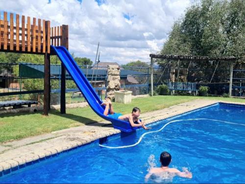 2 personnes sur un toboggan bleu dans une piscine dans l'établissement Eingedi Retreat, à Kommissiepoort