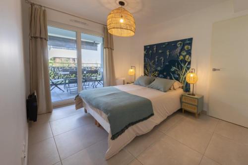 ein Schlafzimmer mit einem Bett und einem großen Fenster in der Unterkunft 06AH - Superb waterfront T2 - swimming pool in Villeneuve-Loubet