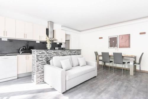 un salon avec un canapé blanc et une table dans l'établissement Appartement ensoleillé Buttes Chaumont - III, à Paris