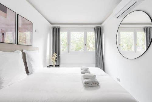 une chambre blanche avec un lit avec des serviettes dessus dans l'établissement Appartement ensoleillé Buttes Chaumont - III, à Paris