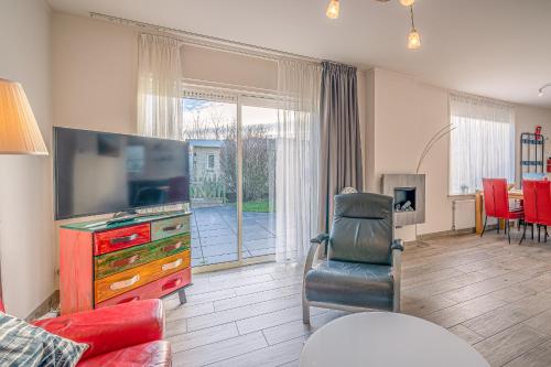 a living room with a flat screen tv and a chair at Californiëweg 9A in De Koog