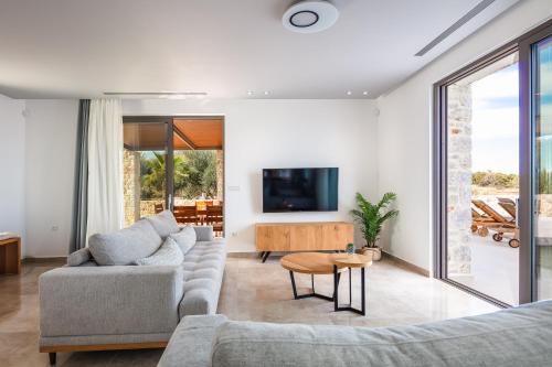 a living room with a couch and a tv at Oinolithos Luxury Villas in Kalamaki