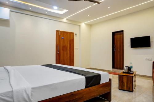 a bedroom with a bed and a tv on the wall at OYO KP Pride in Pune