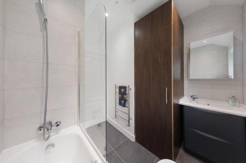 a bathroom with a shower and a tub and a sink at Edgware Oasis: Modern Haven near Tube & Park in Edgware