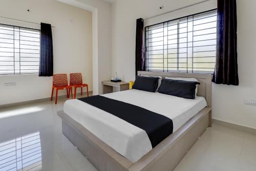 1 dormitorio con 1 cama con 2 sillas y ventanas en OYO Power Spirits Boarding and Lodging, en Bangalore