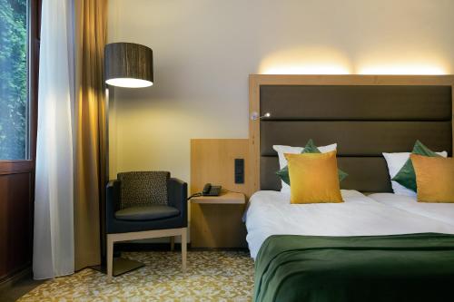 a hotel room with a bed and a chair at Hotel Restaurant Van Der Valk Nivelles-Sud in Nivelles