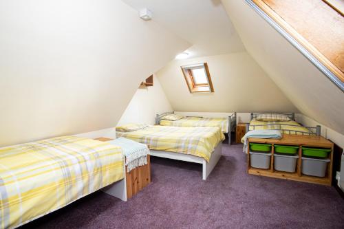 a attic room with three beds and a window at Glenfeshie Hostel in Insh