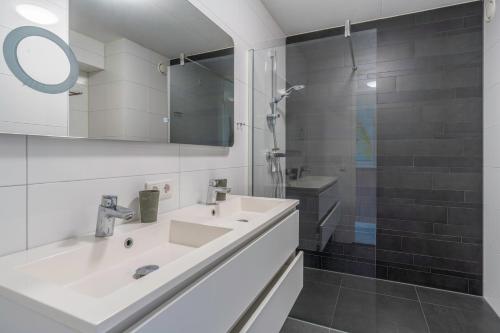 a white bathroom with a sink and a shower at Appartementencomplex Juliana 142 in De Koog