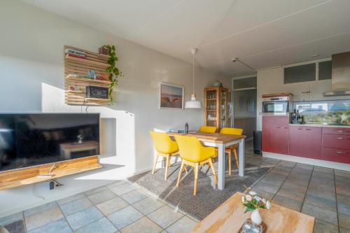 a kitchen and dining room with a table and yellow chairs at Appartementencomplex Juliana 142 in De Koog