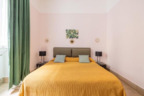 a bedroom with a large yellow bed with green curtains at Domus Castroni Scipioni in Rome