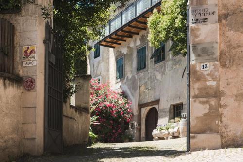 an alley in an old building with pink flowers at Ansitz Rynnhof in Termeno