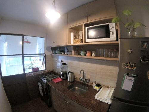 una pequeña cocina con fregadero y microondas en Edificio La Mondiola, en Montevideo