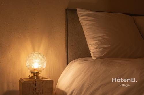 a lamp on a night stand next to a bed at The Lajarlaud Mill - Nature & Charm Along the Water's Edge in Vareilles