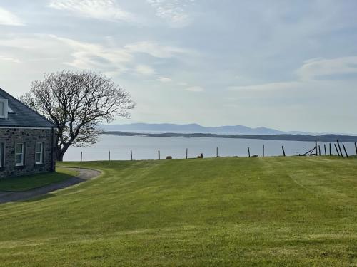a house on a grass field next to a lake at Foxglove Cottage in Killean