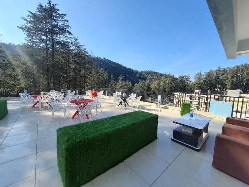 une terrasse avec un canapé vert, des tables et des chaises dans l'établissement JB Hotel and Resort, à Lohaghāt