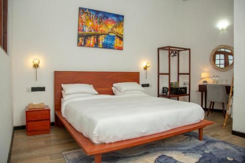 a bedroom with a large bed and a painting on the wall at TIKI TAKA in Kandy