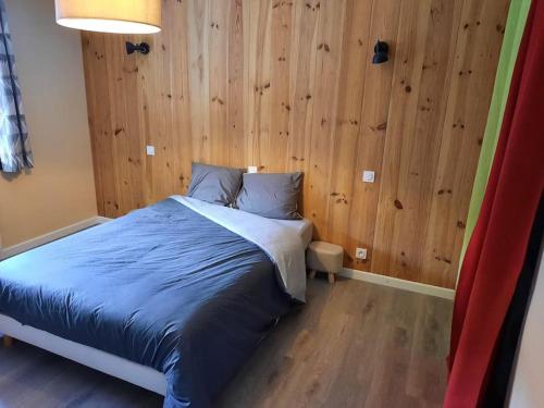 a bedroom with a bed with a wooden wall at Appartement tout confort , centre Loudenvielle in Loudenvielle