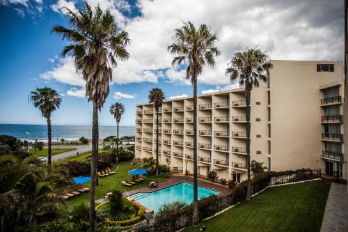 an exterior view of a hotel with palm trees and a swimming pool at Garden Court East London in East London