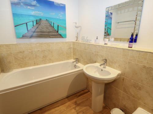 a bathroom with a tub and a sink and a pier painting at Lark Meadow in Carnforth