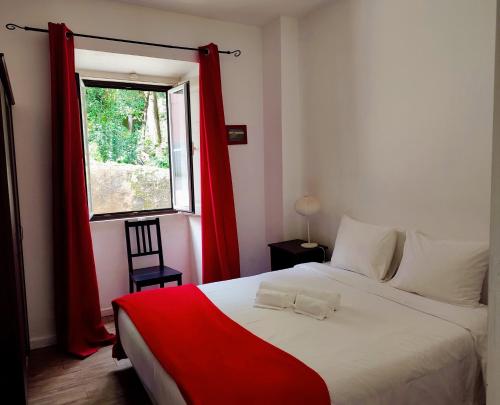 a bedroom with a bed with red curtains and a window at Casas da Biquinha in Sintra