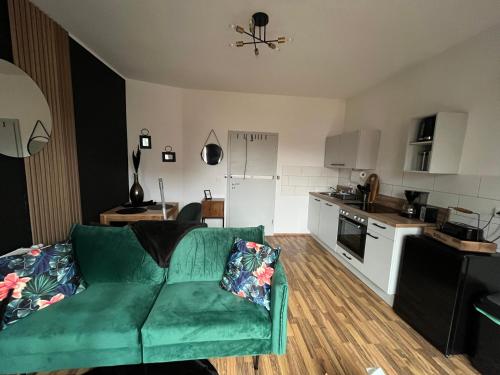 a living room with a green couch and a kitchen at Fewo Living Home in Magdeburg