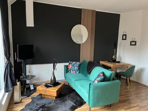 sala de estar con sofá verde y pared negra en Fewo Living Home, en Magdeburgo