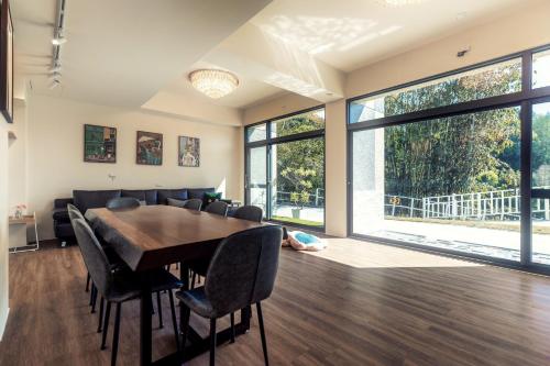 a dining room with a table and chairs and large windows at Peachland in Puli
