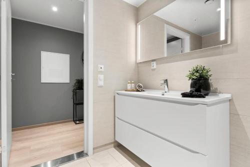 ein weißes Badezimmer mit einem Waschbecken und einem Spiegel in der Unterkunft Moderne Leilighet med 2soverom Sentral beliggenhet in Asker