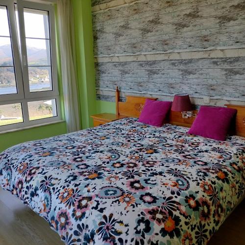a bedroom with a bed with a floral comforter and two windows at Hotel Capellan in Navia