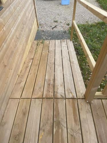 a wooden deck with a bench in the grass at Tiny house au cœur du marais in Saint-Omer