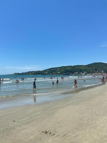 a group of people in the water at the beach at Pousada Santa Terezinha in Garopaba