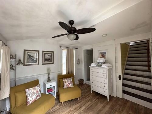een woonkamer met een plafondventilator en 2 stoelen bij Caretakers Apartment-Split level w/ European Bath in Wolfeboro