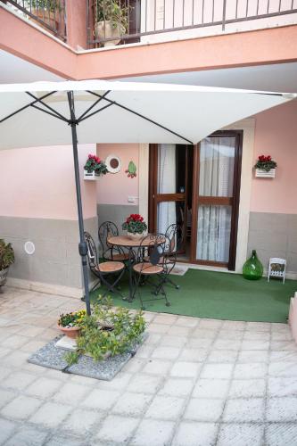 a patio with a table and chairs under an umbrella at B&B Flower House in Fasano