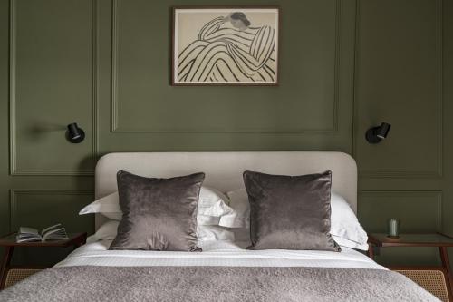 a bed with two pillows in a green bedroom at Bryony Cottage: Close to Station in Windermere