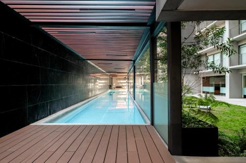 a swimming pool in a building with a wooden deck at Lumina at Taman Condesa in Mexico City