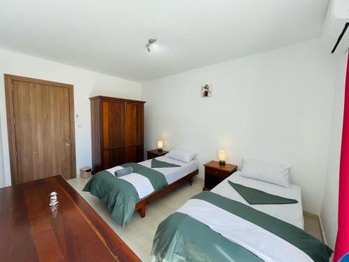 a bedroom with two beds and a wooden table at Coral Cove Comfort Room 2 in St Paul's Bay