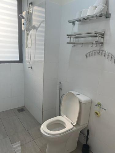 a white bathroom with a toilet and a shower at Yuyu Star Suites in Kampong Bekoh