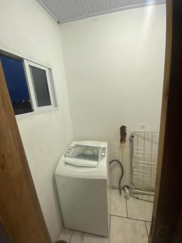 a washing machine in a white room with a window at Residência Ever’s in Jaguaruna