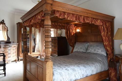 a bedroom with a canopy bed with a wooden frame at Warwick Centre Townhouse in Warwick