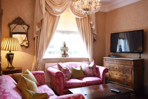 ein Wohnzimmer mit einem rosa Sofa und einem Fenster in der Unterkunft Warwick Centre Townhouse in Warwick