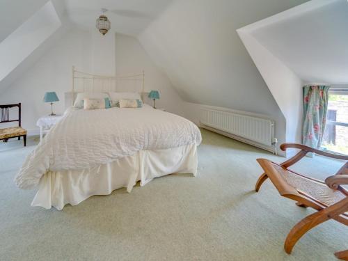 een witte slaapkamer met een bed en een stoel bij 2 Bed in Isle of Purbeck IC096 in Corfe Castle