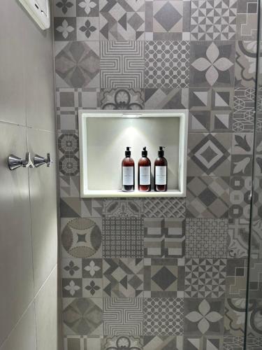dos botellas de vino sentadas en un estante en un baño en Apartamento Vista Mar aconchegante no Rio Vermelho, en Salvador