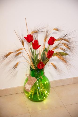 a green vase with red roses in it at B&B Flower House in Fasano