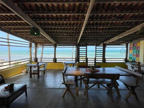een eetkamer met tafels en uitzicht op de oceaan bij Pousada Parracho in Maracajaú