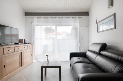 ein Wohnzimmer mit einem Ledersofa und einem Tisch in der Unterkunft Maison Rhéa in Rivedoux-Plage