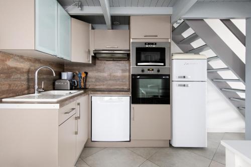 een keuken met witte apparatuur en een trap bij Maison Rhéa in Rivedoux-Plage